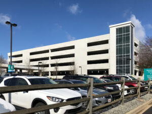Asheville Regional Airport parking structure exterior on sunny day with cars in surface lot in foreground