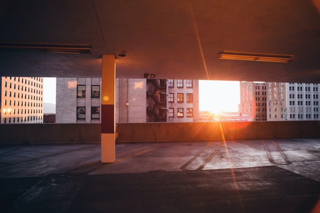 Empty parking garage with skyscrapers and sunset visible in background