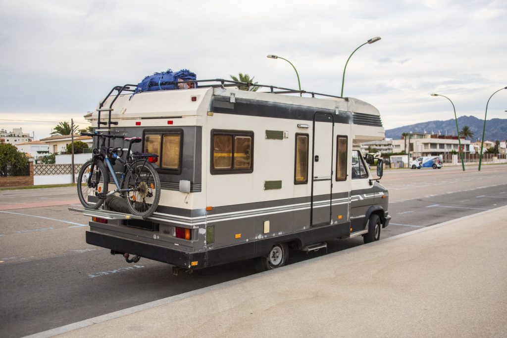 An inhabited recreational vehicle parallel parked on a street