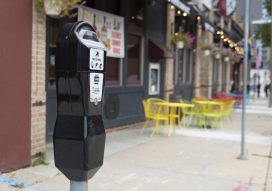A parking meter for a curb space with sidewalk dining in the background