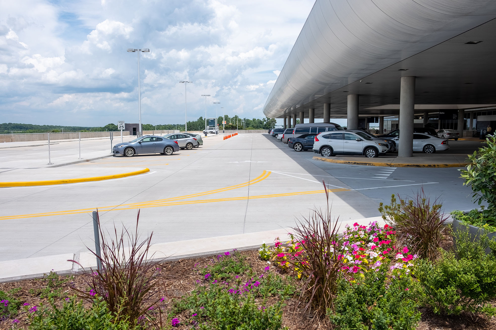 Elevated roadway at PTIA with terminal, parked cars, and landscaping in foreground