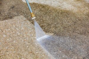 Close-up of a pressure washing nozzle cleaning a concrete surface with a jet of water