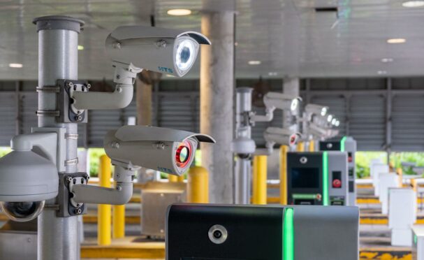 A row of license plate reader cameras at the entrance/exit lanes of a parking structure