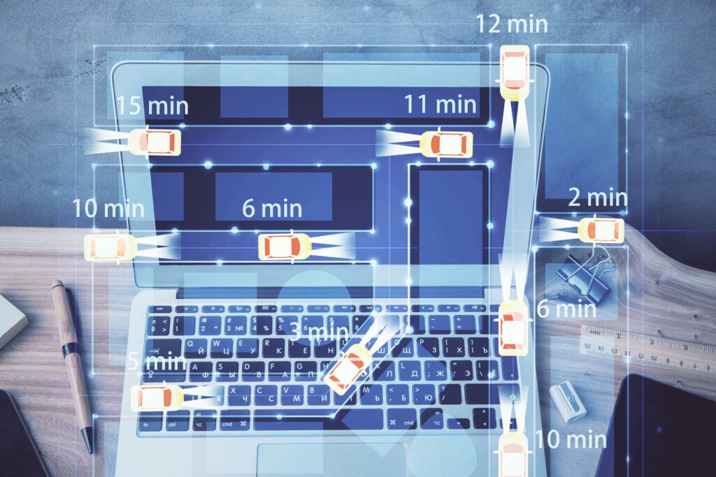 Abstract graphic of vehicle icons with routes and time estimates overlaid on a photo of a laptop on a desk