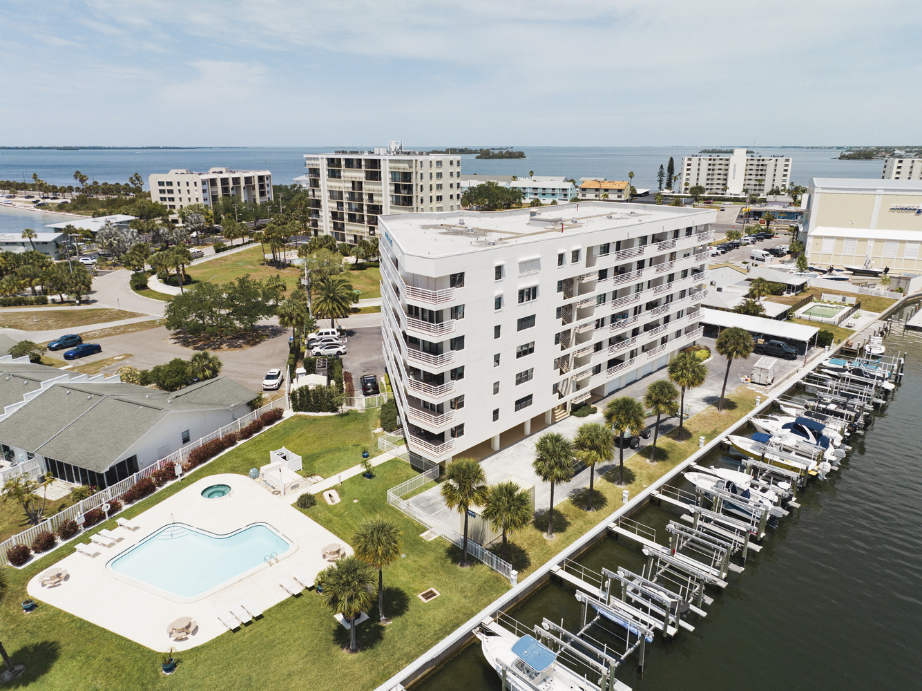 Marina Place condo seen from above, with swimming pool, palm trees, and harbor full of boats in the foreground